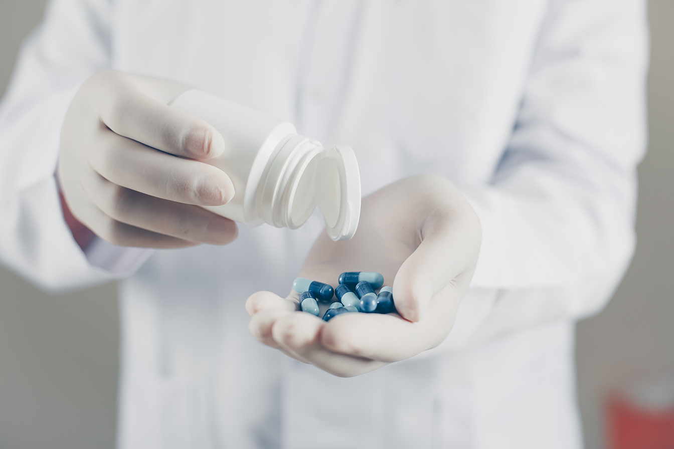 Side view doctor with gloves holding pills and bottle